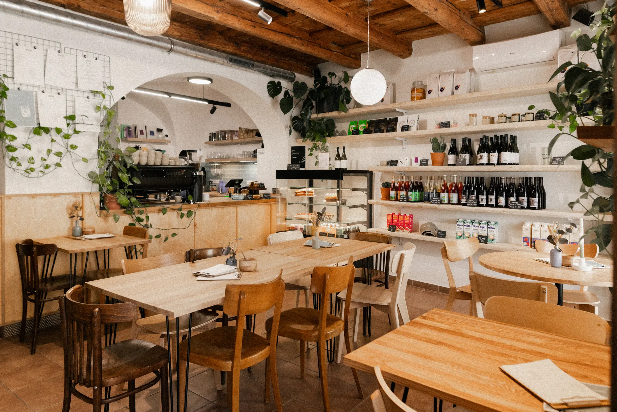 Interiér MOJI café — klenba, dřevěný strop a dřevěné stoly